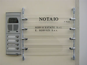 Composizione di targhe in plexiglass trasparente con testi retroincisi e smaltati in colore nero. Targa fissata al muro per mezzo di pinze e astine in ottone cromato tinta argento lucido