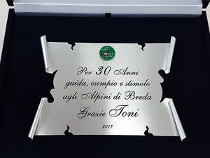 Targa ringraziamento in silver plated a forma di pergamena con dedica incisa ed annerita con ossido. Tondino in plexiglass e stemma alpini applicato. Completa di astuccio in velluto blu e cielo in raso bianco