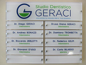 composizione di targhe per studio dentistico realizzate in plexiglass trasparente con logo e nomi retrostampati e fissate con distanziatori su astine in plexiglass