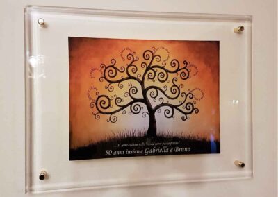 targa per 50°anniversario di matrimonio in plexiglass trasparente con bordi bisellati lucidi con immagine stampata sul retro e dedica in rilievo fissata al muro con distanziatori