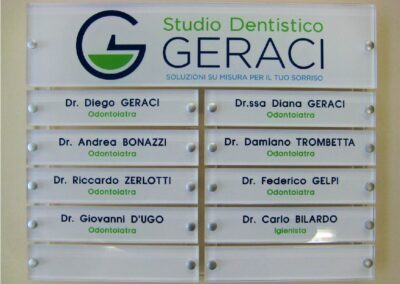 composizione di targhe per studio dentistico in plexiglass fondo bianco con logo e testi stampati a colori fissate con distanziatori in alluminio su astine in plexiglass trasparente